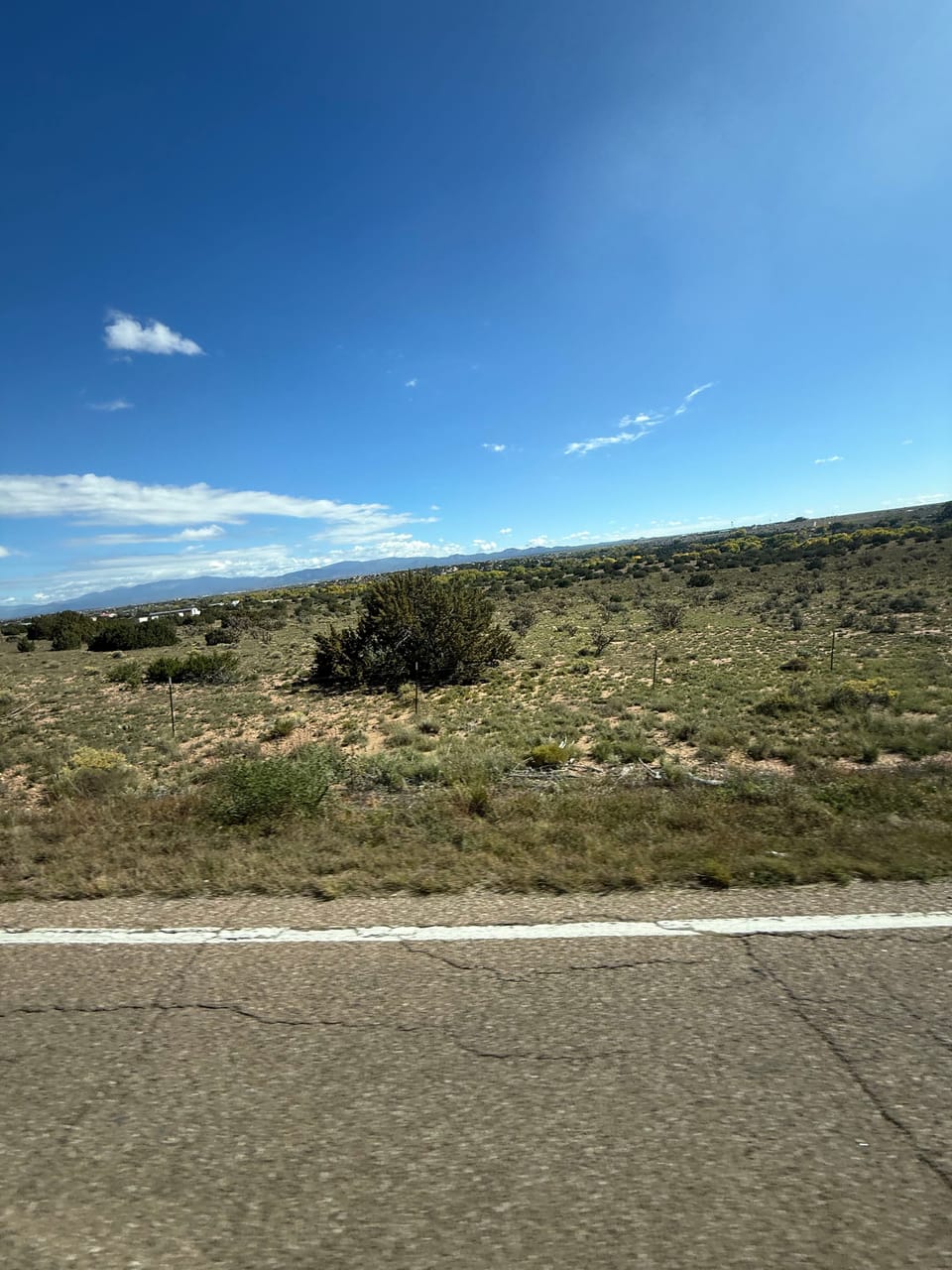 Open scrubland and a wide blue sky beside the highway on the road to Albuquerque