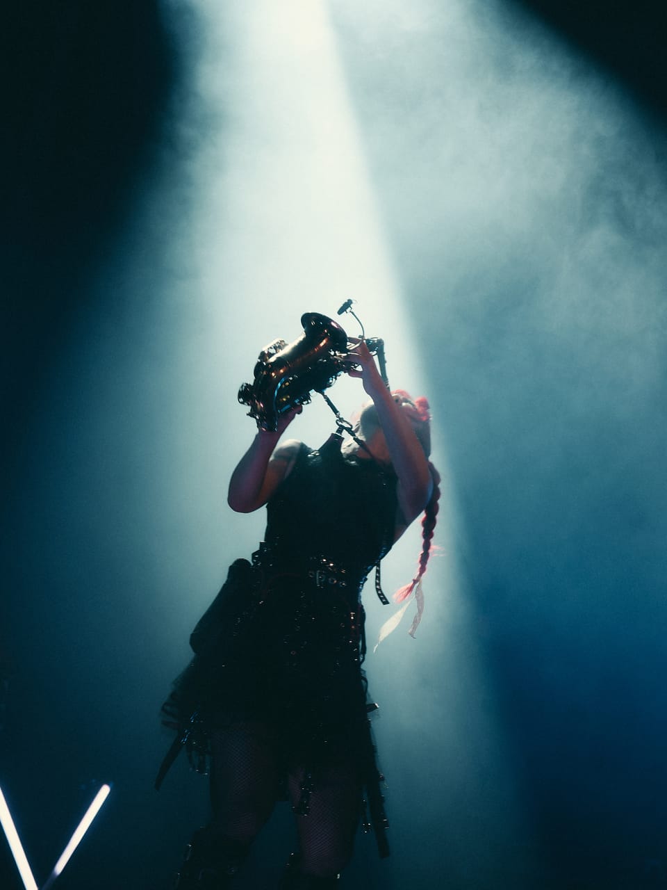 Grace Kelly raises her saxophone straight up into a spotlight through blue haze at the Oriental Theater in Denver