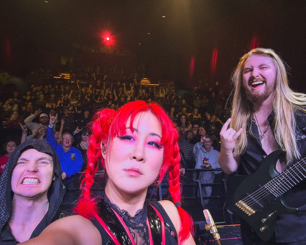 Grace Kelly takes a selfie on stage at the Mesa Theater with drummer Kyle Brian and guitarist Sam Fairless, the Grand Junction crowd throwing horns behind them