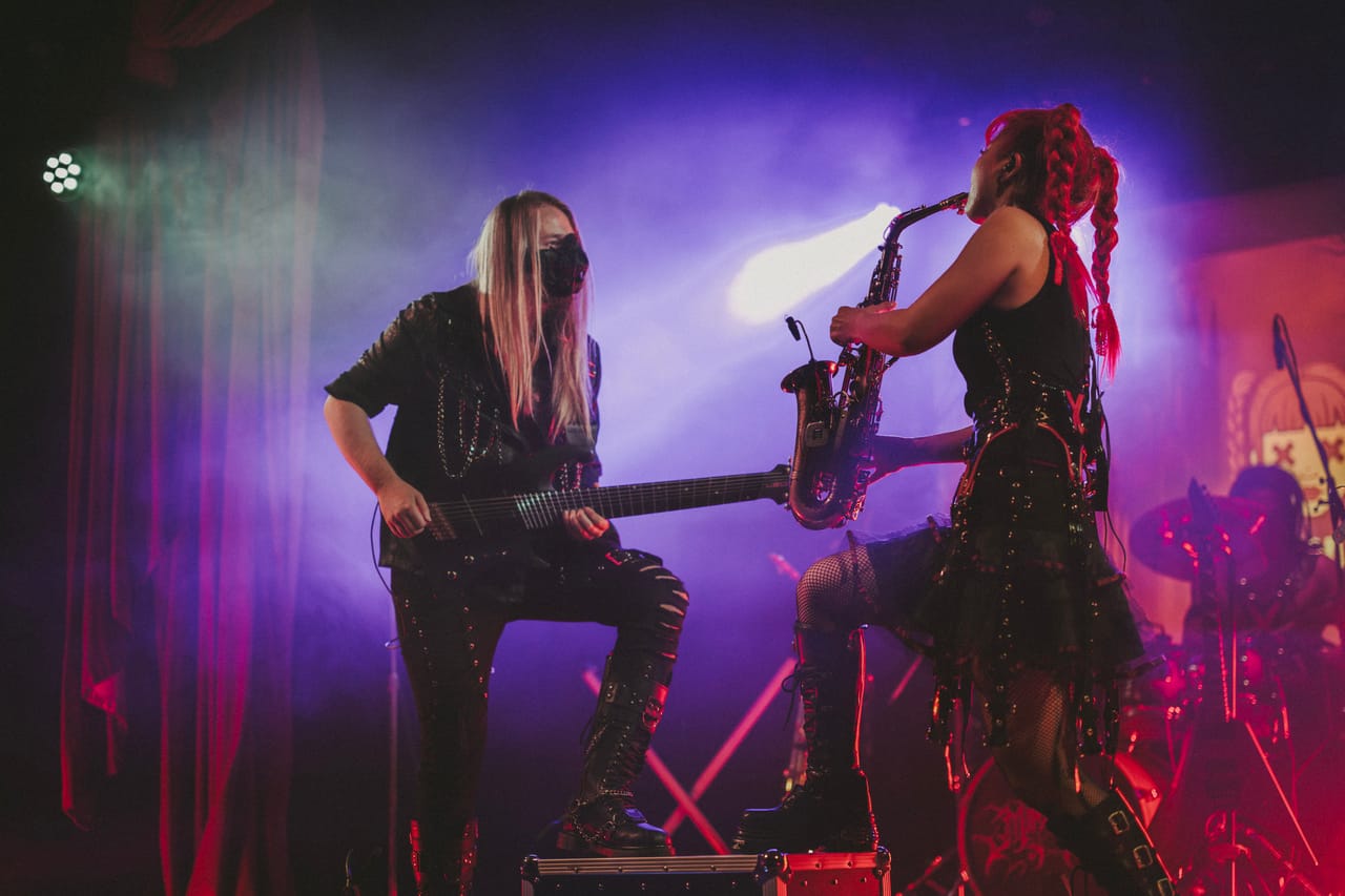 Sam Fairless, one boot on a road case, plays guitar face to face with Grace Kelly on saxophone through purple haze at the Star Theater in Portland
