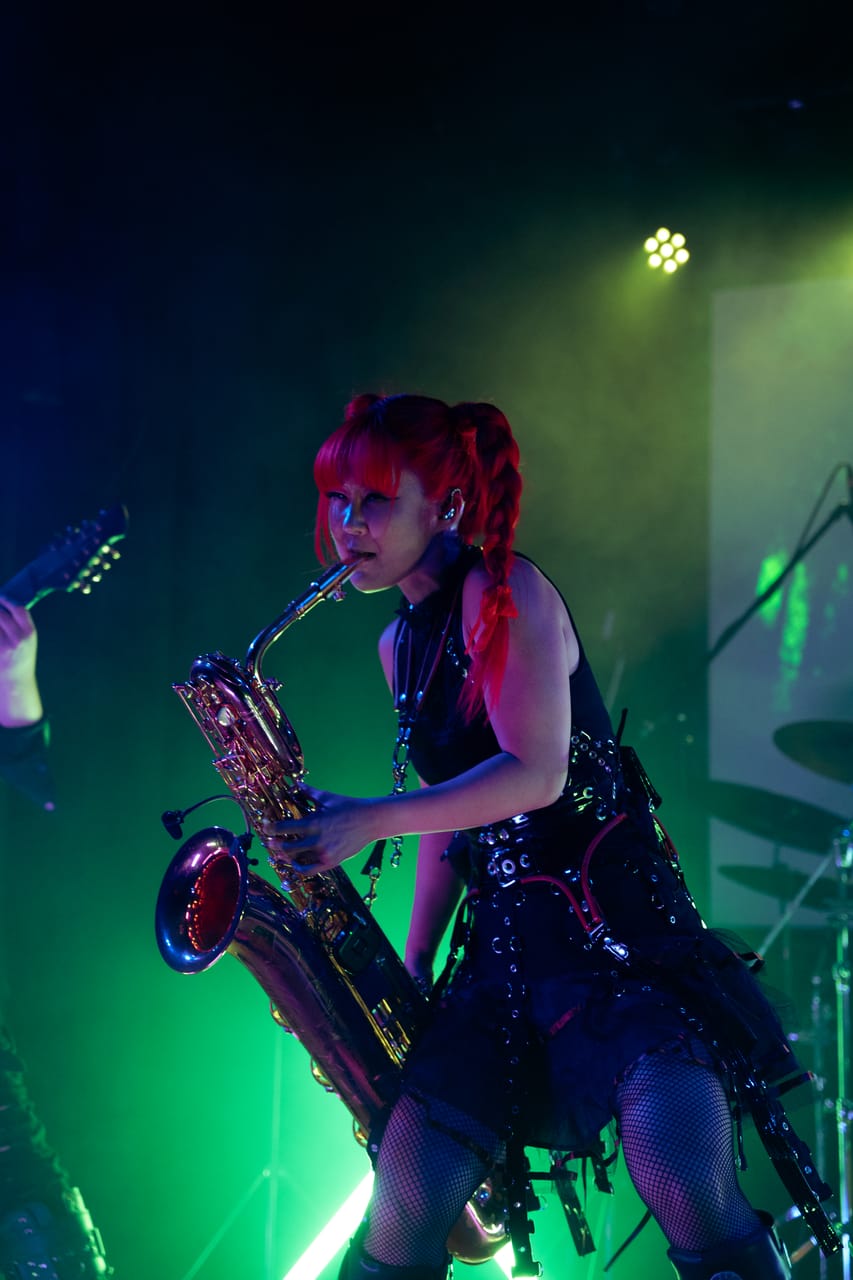 Grace Kelly plays baritone saxophone under green light at the Star Theater in Portland