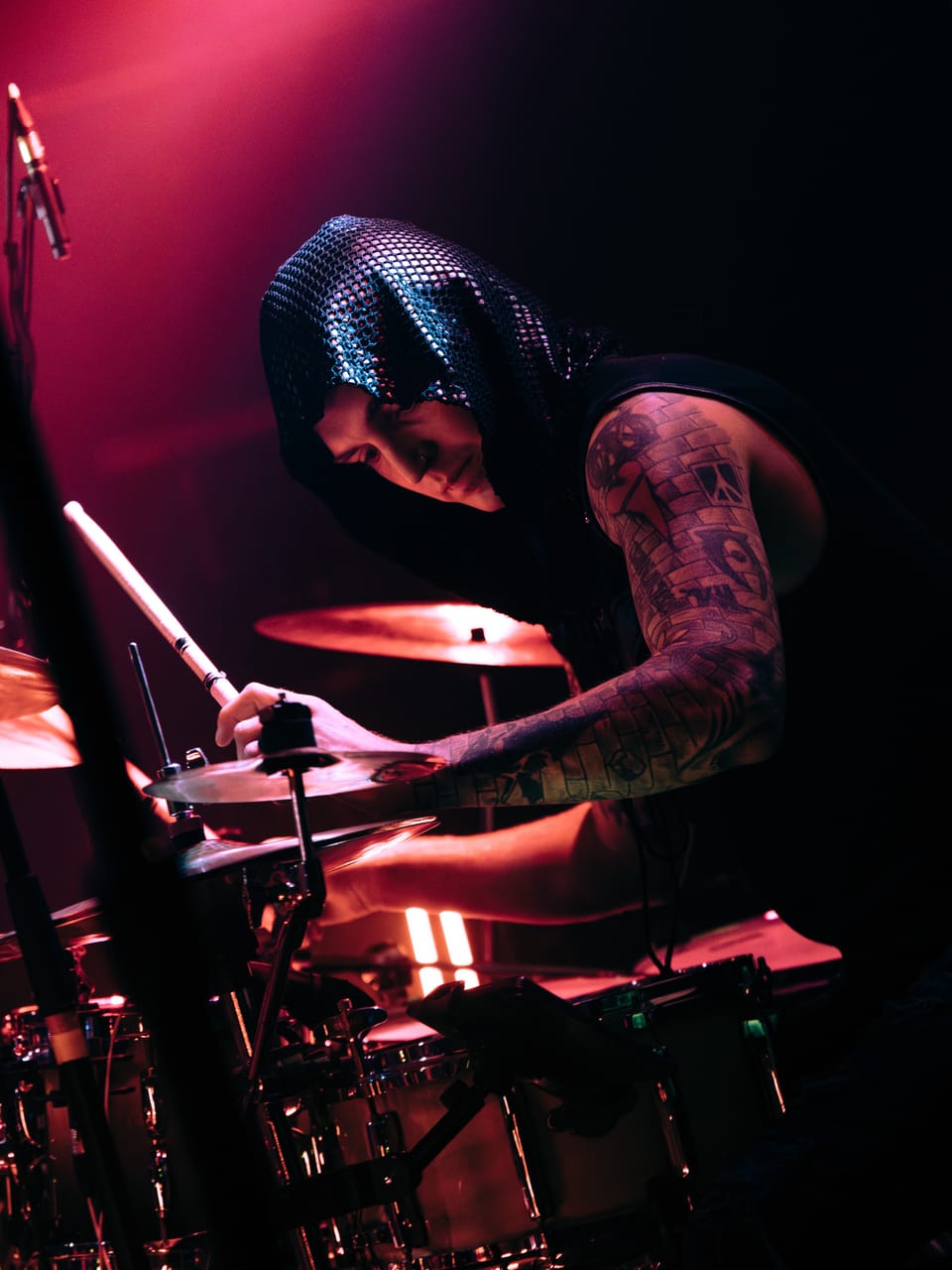 DEADGRACE drummer Kyle Brian, in a sequined hood with tattooed arms, plays behind the cymbals under red light at the Urban Lounge, Salt Lake City