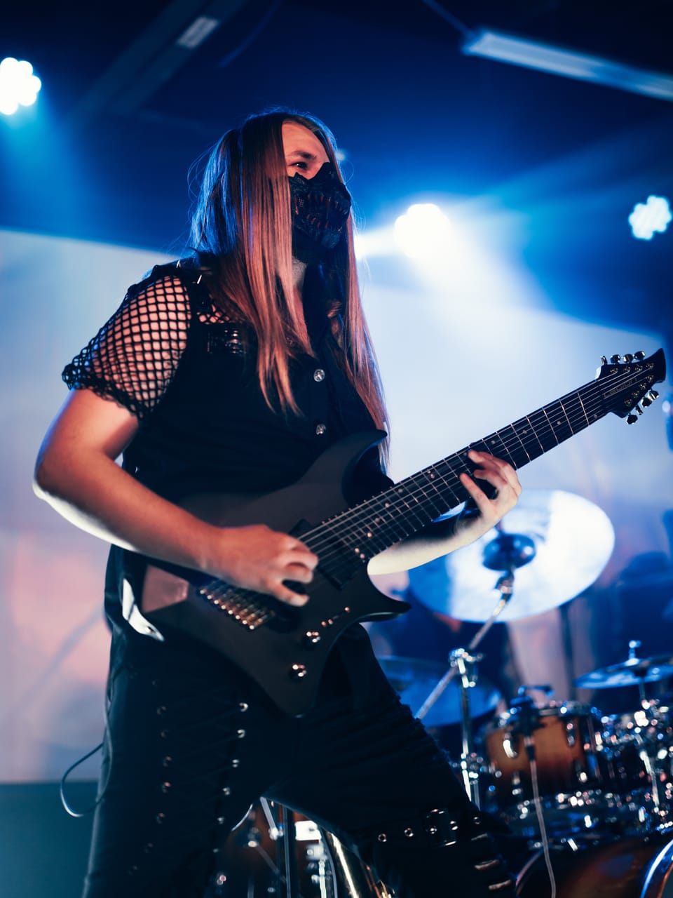 DEADGRACE guitarist Sam Fairless, long hair and a black mask, plays a black guitar in blue stage light at the Urban Lounge, Salt Lake City, the drum kit behind him