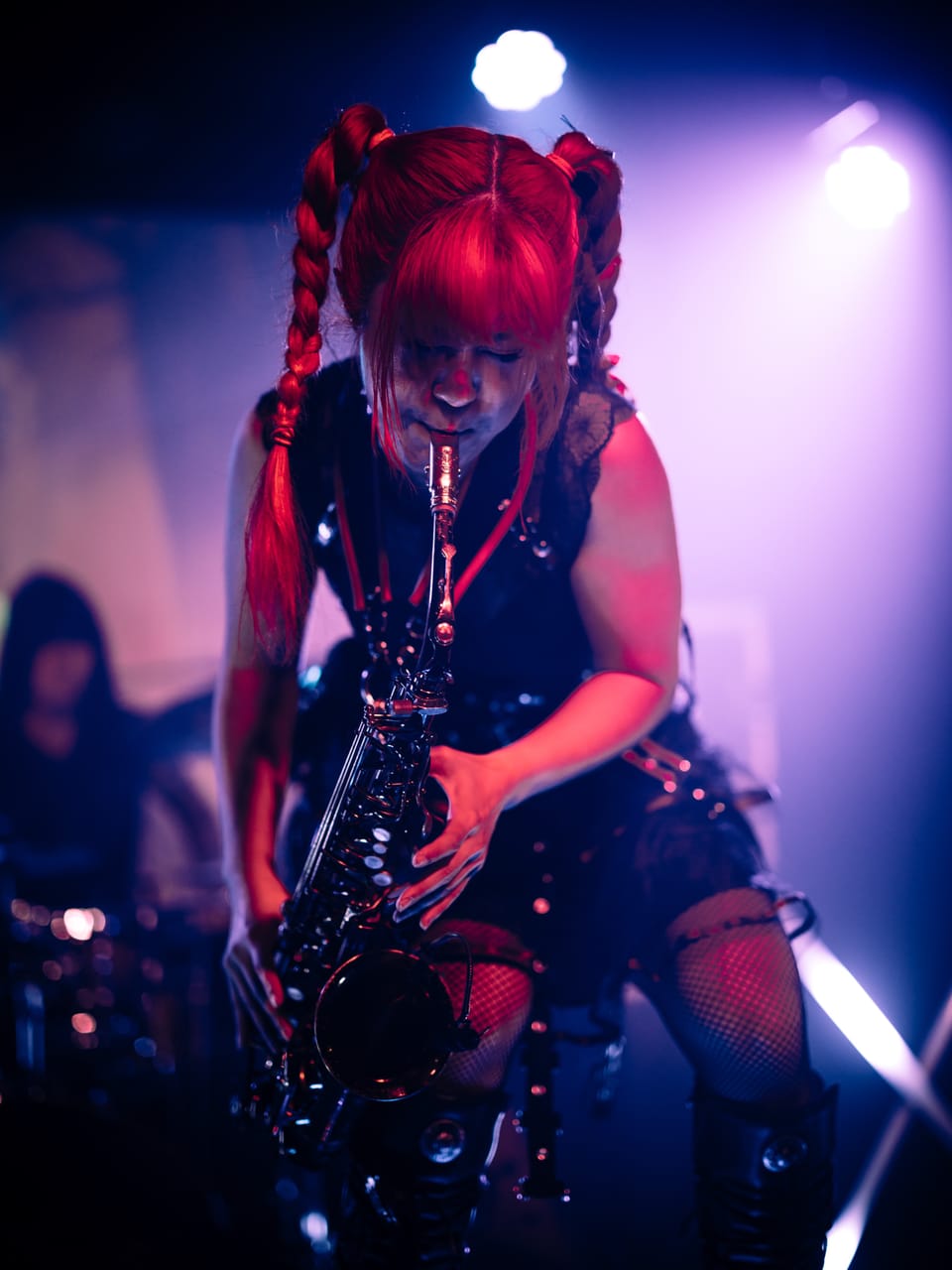 Grace Kelly bends low into her saxophone, red braids hanging forward, under red and purple stage light at the Urban Lounge in Salt Lake City