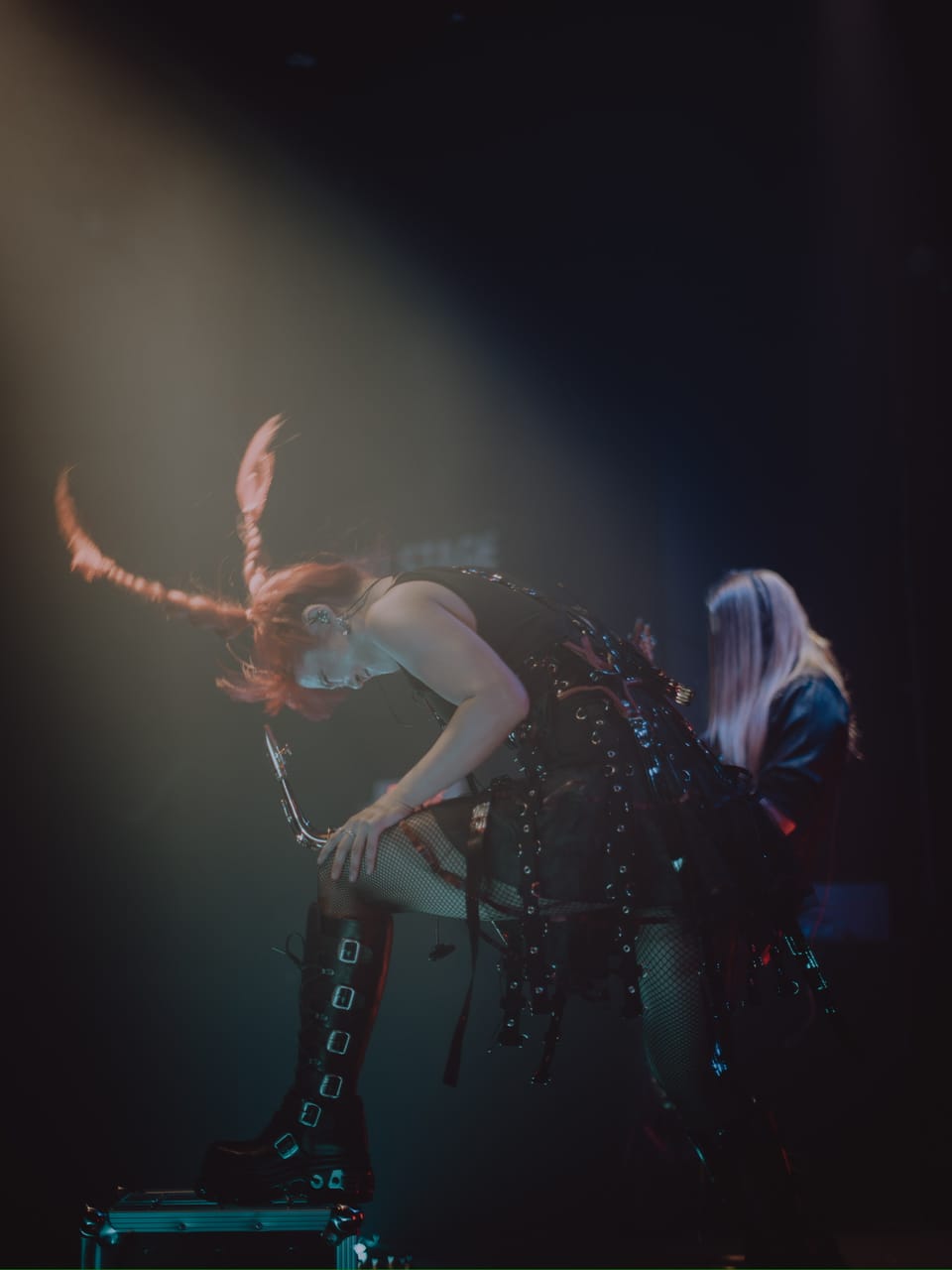 Grace Kelly headbangs with her red braids whipping through a spotlight, one boot up on a road case and a saxophone in hand, as guitarist Sam Fairless plays behind her