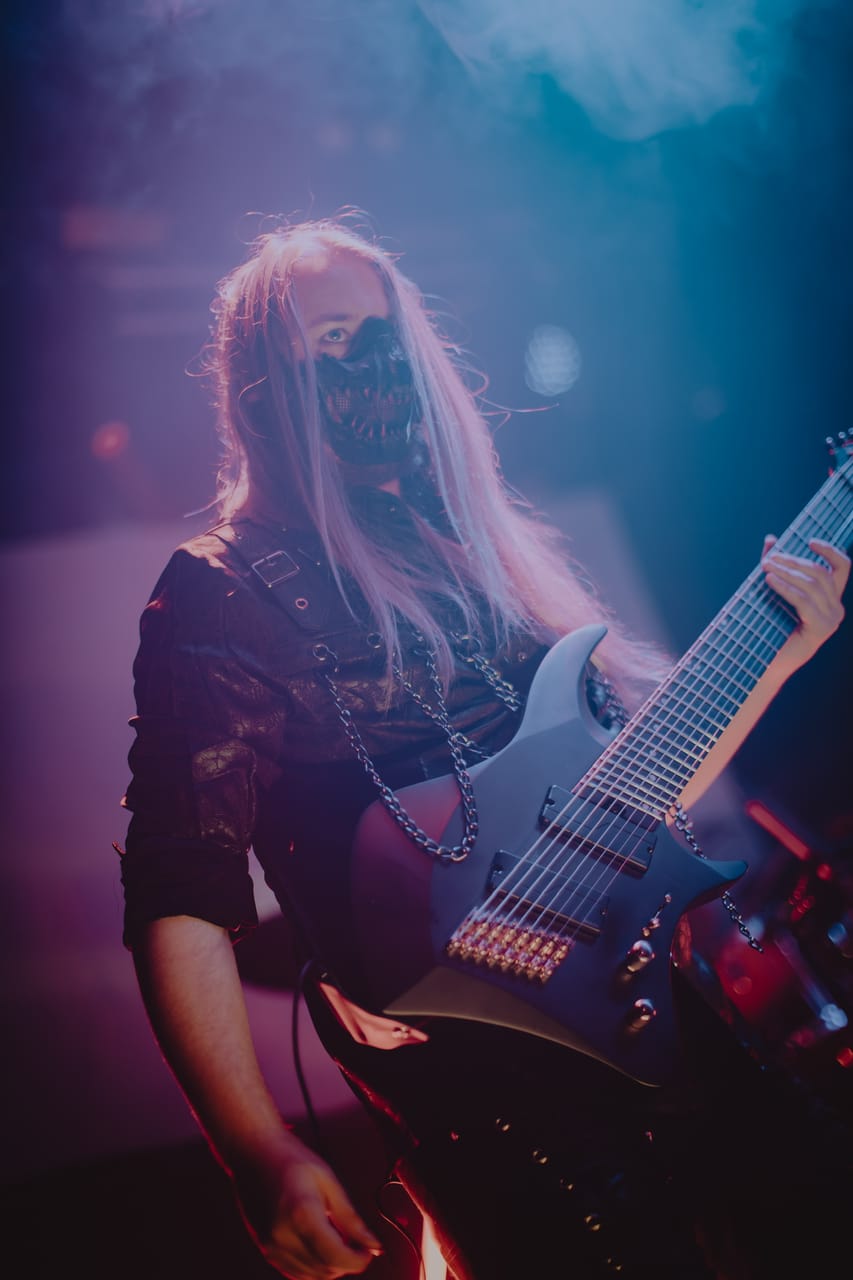 Close-up of DEADGRACE guitarist Sam Fairless in a black skull-style mask and chains, playing an 8-string guitar at The Ritz, San Jose