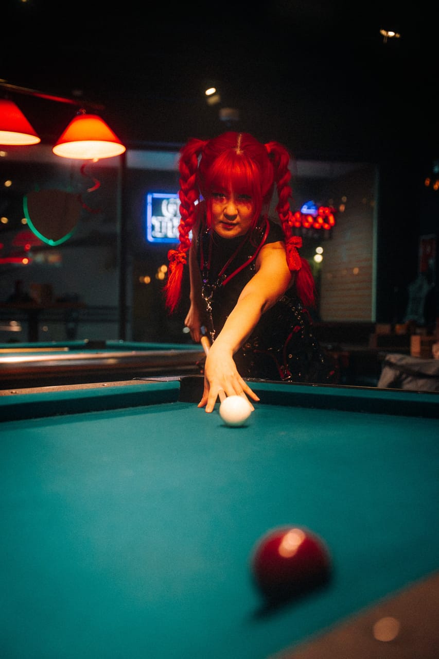 Grace Kelly leans over the pool table to take a shot, a red ball in the foreground, at The District in Spokane